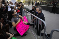 Los Angeles Police Chief Michel Moore reaches through a crowd control barrier to shake hands with a demonstrator while taking a knee during a protest over the death of George Floyd, Thursday, June 4, 2020, in Los Angeles. Floyd, an African American man, died on May 25 after a white Minneapolis police officer pressed a knee into his neck for several minutes even after he stopped moving and pleading for air. (AP Photo/Jae C. Hong)