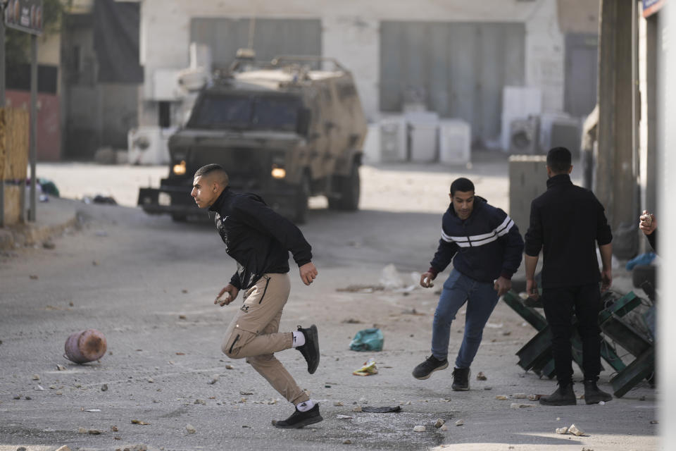 Palestinians clash with Israeli forces following an army raid in the West Bank city of Jenin, Thursday, Jan. 26, 2023. Israeli forces killed at least nine Palestinians, including a 60-year-old woman, and wounded several others during a raid in a flashpoint area of the occupied West Bank on Thursday, Palestinian health officials said, in one of the deadliest days in months of unrest. The Israeli military said it was conducting an operation to arrest a militant grouping linked to the Palestinian Islamic Jihad, which has major foothold in the camp. A gun battle erupted, during which the military said it was targeting militants involved in planning and carrying out attacks on Israelis. (AP Photo/Majdi Mohammed)