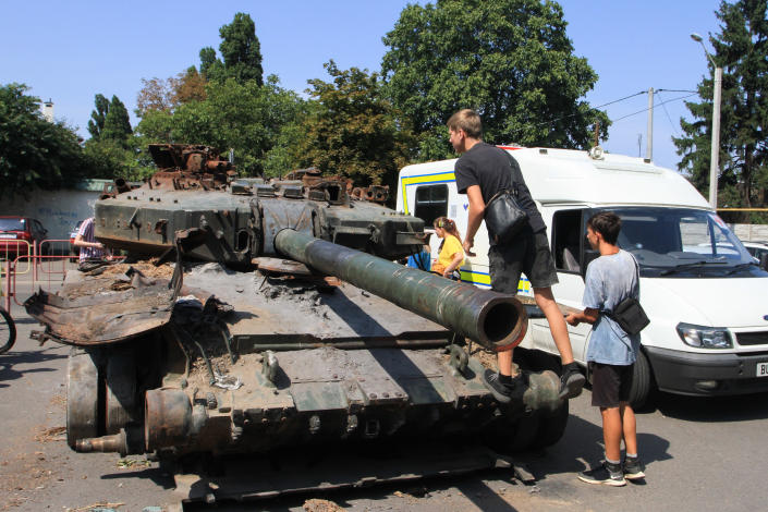 Teenagers are seen near the burned-out Russian T-90 tank. Units of the operational command 