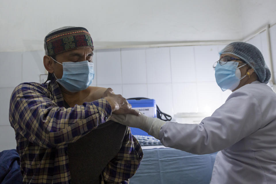 A health worker rubs the arm of her husband, who works in the same hospital, after administering COVID-19 vaccine at the Zonal Hospital in Dharmsala, India, Monday, Jan. 18, 2021. India started inoculating health workers Saturday in what is likely the world's largest COVID-19 vaccination campaign, joining the ranks of wealthier nations where the effort is already well underway. (AP Photo/Ashwini Bhatia)