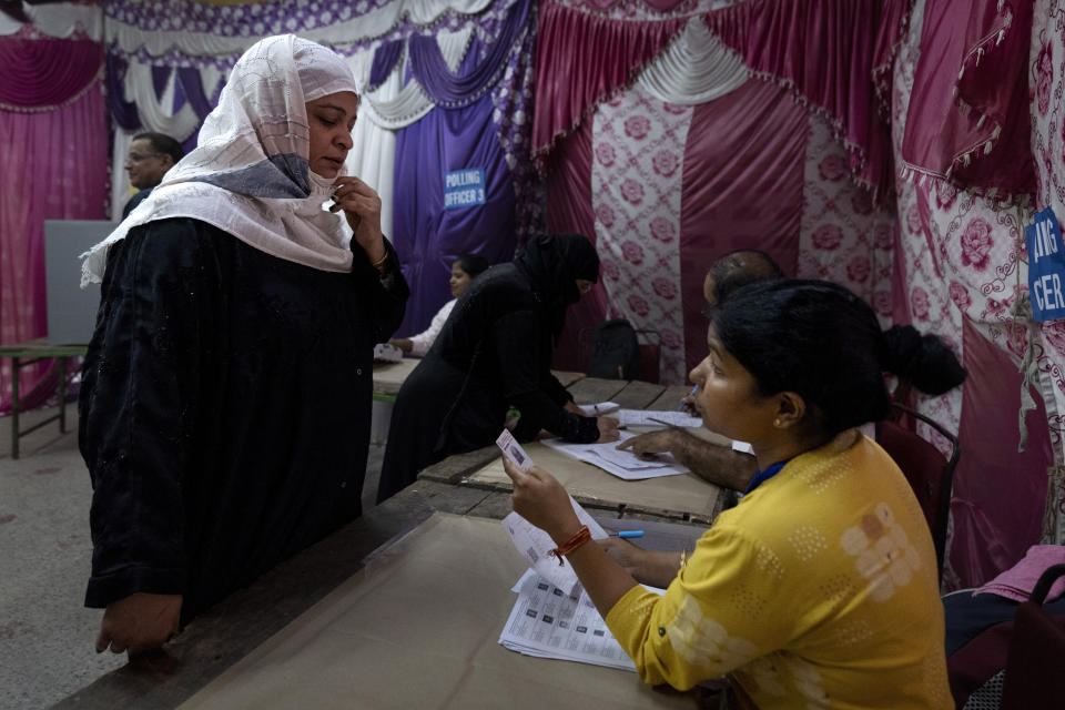 A polling official inspects the identity card of a Muslim voter as she arrives to cast her vote in the sixth round of polling in India's national election in New Delhi, India, Saturday, May 25, 2024. (AP Photo/Altaf Qadri)