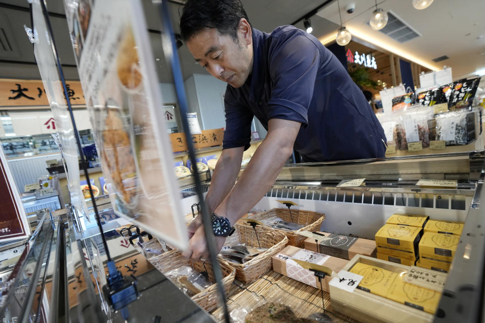 Katsumasa Okawa, owner of Okawa Fish Store, arranges fish products at his store in Iwaki, northeastern Japan on Friday, Aug. 25, 2023. Fish auction prices at a port south of the Fukushima Daiichi nuclear power plant Friday somehow dipped amid uncertainty about how consumers may respond a day after release to sea of treated and diluted radioactive wastewater began despite protests at home and in neighboring countries. (AP Photo/Eugene Hoshiko)