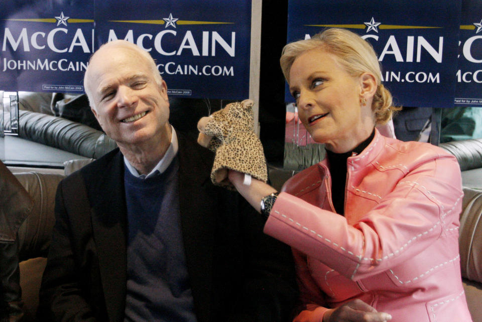 FILE - In this Jan. 19, 2008, file photo, Cindy McCain, wife of Republican presidential hopeful Sen. John McCain, R-Ariz., uses a cheetah hand puppet to make her husband laugh as they ride the "Straight Talk Express" campaign bus to a polling station in Charleston, S.C., on the day of South Carolina's Republican presidential primary. Arizona Sen. McCain, the war hero who became the GOP's standard-bearer in the 2008 election, has died. He was 81. His office says McCain died Saturday, Aug. 25, 2018. He had battled brain cancer. (AP Photo/Charles Dharapak, File)