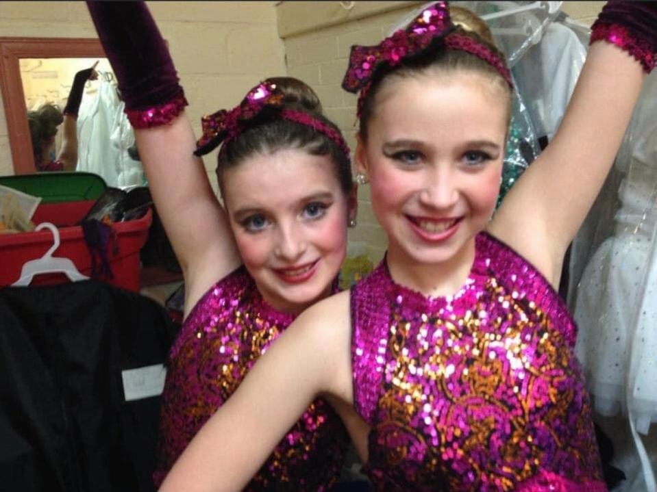 Two teenagers dressed in sequin dance costumes.