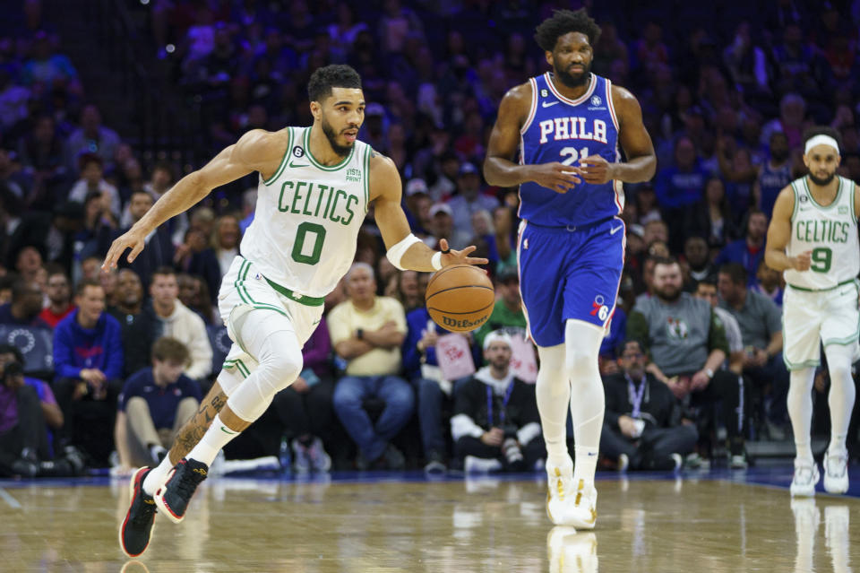 Boston Celtics' Jayson Tatum, left, brings the ball up as Philadelphia 76ers' Joel Embiid, center, watches during the first half of an NBA basketball game Tuesday, April 4, 2023, in Philadelphia. (AP Photo/Chris Szagola)