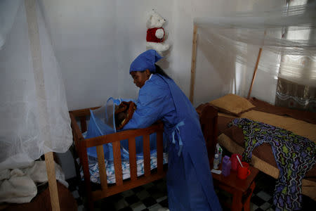 Ruth LaFleurissante, Ebola survivor who works as a caregiver, holds an infant at a United Nations Children's Fund (UNICEF) creche for children whose families are suspected or confirmed Ebola cases, near the Ebola treatment centre in Butembo, Democratic Republic of Congo, March 26, 2019. Picture taken March 26, 2019. REUTERS/Baz Ratner