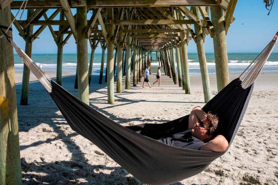 A local man relaxes in a hammock under the pier in Garden City Beach, S.C. on Friday. Grand strand residents and visitors head for the beach on the first sunny weekend of Spring. March 24, 2023.