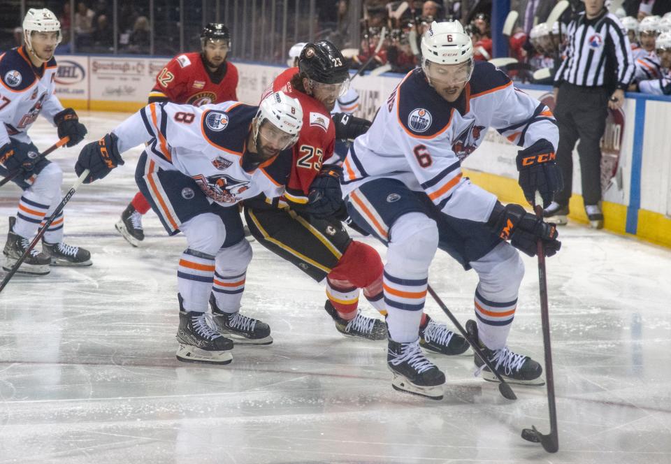 Stockton Heat's Justin Kirkland, center, fights for the puck with Bakersfield Condors' Yanni Kaldis, left, and Vincent Desharnais during the second game of the Calder Cup playoffs Wednesday at Stockton Arena.