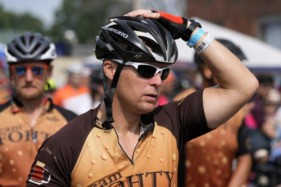 Associated Press reporter Dave Skretta, center, walks his bike through town while riding in The Des Moines Register's annual bike ride across Iowa, also known as RAGBRAI, Tuesday, July 25, 2023, in Rippey, Iowa. (AP Photo/Charlie Neibergall)