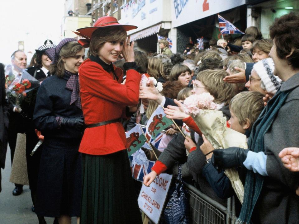 princess diana greeting fans wearing a red suit and hat