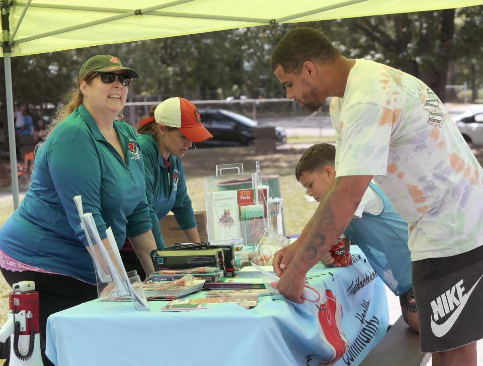 Alliance City Health Department's Director of Nursing Melissa Rudolph, left, and coordinator Leslie Shaffer provide information and small goodies to Jared Perrine, right, and his son Grayson, 8, at the annual Back to School and Community Day on Saturday, Aug. 12, 2023, at Thompson Snodgrass Park.