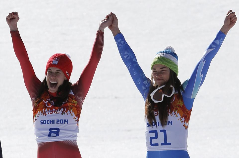 Women's downhill gold medalists Switzerland's Dominique Gisin, left, and Slovenia's Tina Maze, right, hold hands during a flower ceremony at the Sochi 2014 Winter Olympics, Wednesday, Feb. 12, 2014, in Krasnaya Polyana, Russia. (AP Photo/Christophe Ena)