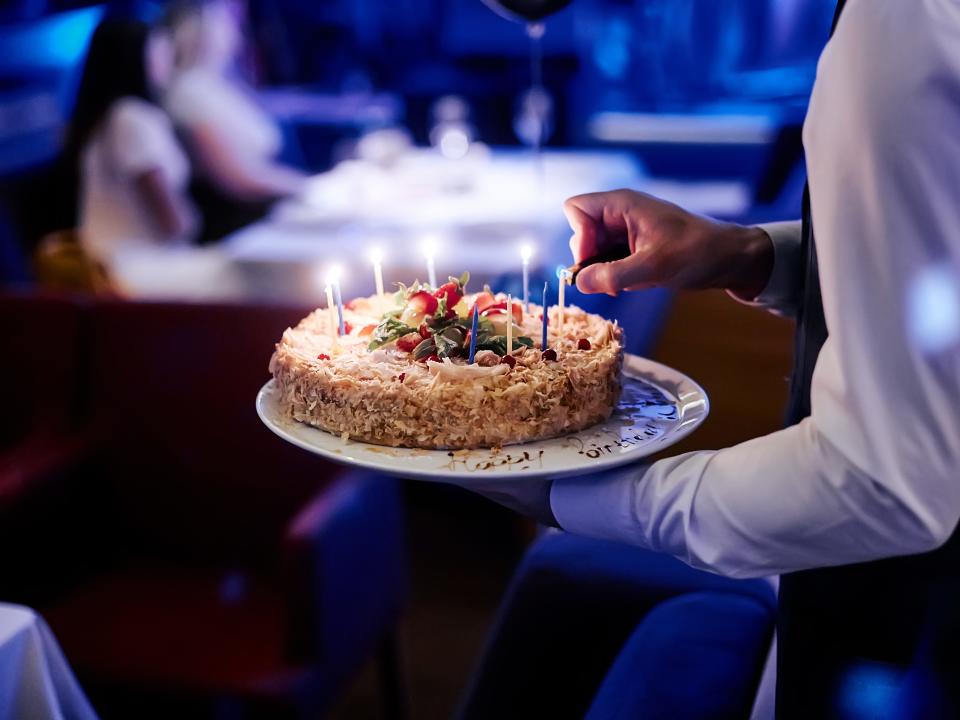 server carrying a birthday cake to a table