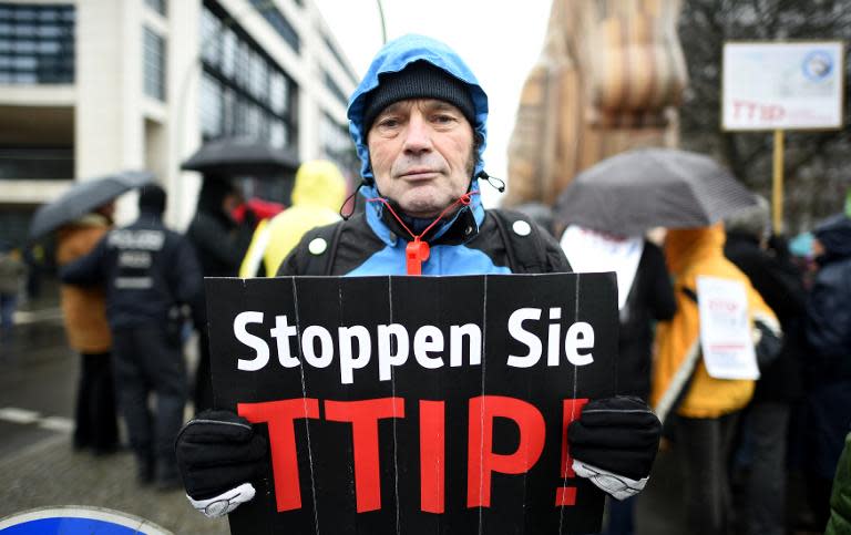 A protester holds up a sign reading: "Stop TTIP!" in front of the headquarters of Germany's Social Democratic Party SPD in Berlin prior to a conference on Transatlantic Trading on February 23, 2015