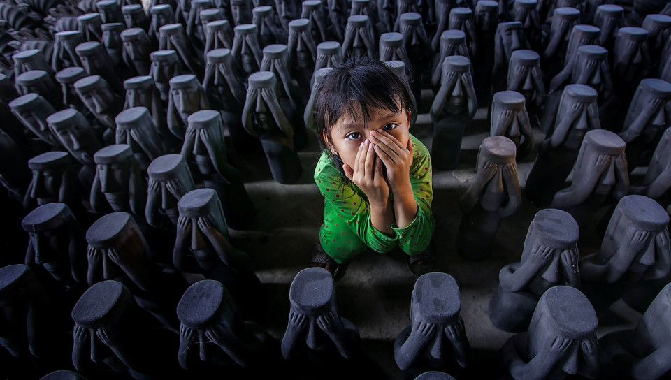The photographer snapped this photo after this little girl followed her mother to their pottery factory in Vietnam.