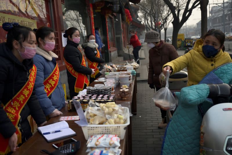 People wearing face masks buy food from a stall set up by a restaurant in Beijing