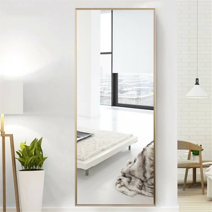 a gold-tone mirror hung on a wall in a room