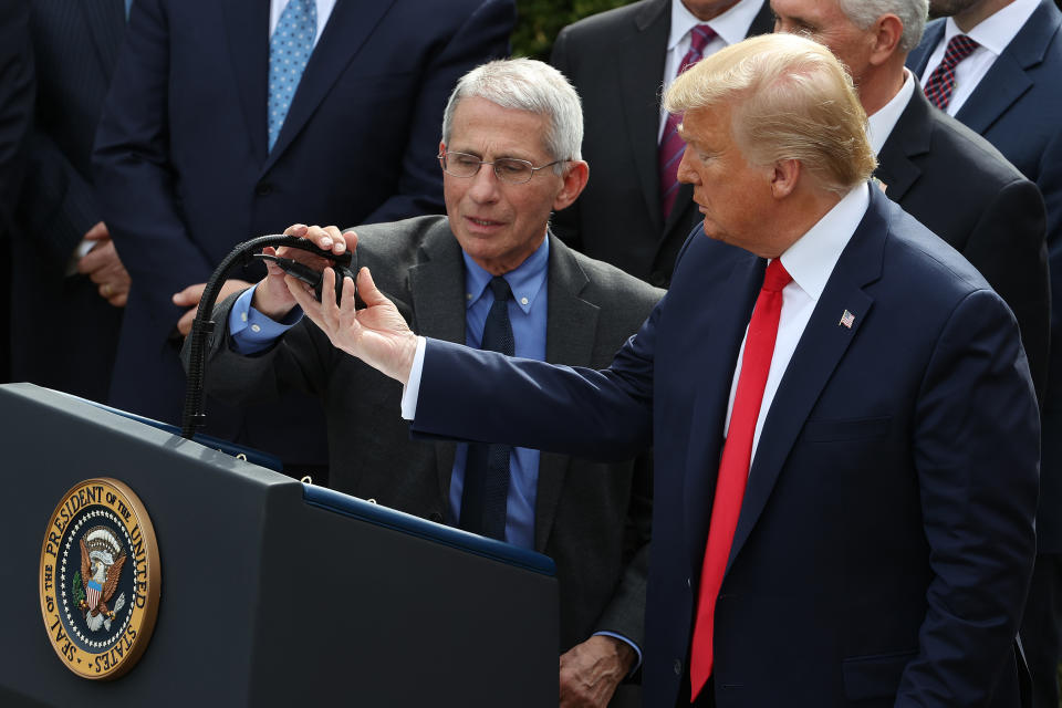 President Trump adjusts the microphone for National Institute Of Allergy And Infectious Diseases director Anthony Fauci during a news conference. (Chip Somodevilla/Getty Images)