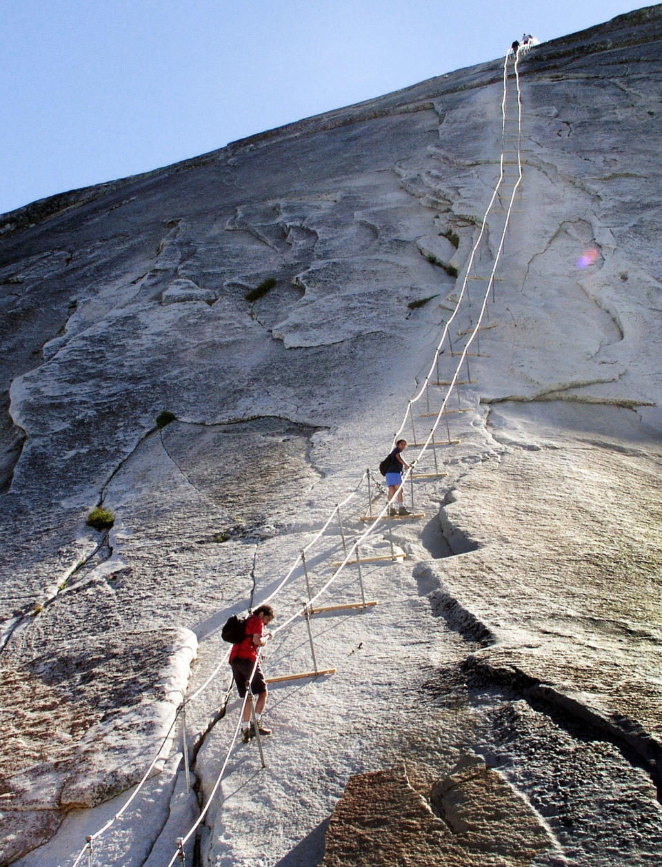 FILE - In this June 6, 2004 file photo, hikers descend the cable route after climbing to the summit of Half Dome, in Yosemite National Park. The trail of dirt and hundreds of feet of twisted metal cables might not immediately conjure an image of something worthy of historical preservation. But when the trail leads to the iconic Half Dome in Yosemite National Park and the cables allow armchair wilderness lovers to ascend the once-inaccessible granite monolith, the significance becomes enough for listing on the National Register of Historic Places. While such a move might go unnoticed, as it did last month, the timing and significance are critical as Half Dome hikers and wilderness advocates await the park’s final assessment of a plan to permanently limit access to a place on many outdoor lovers’ bucket lists. (AP Photo/Robert F. Bukaty)