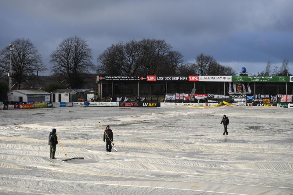 Staff clear water off the pitch covers at Victory Park, where Chorley host WolvesAFP via Getty Images