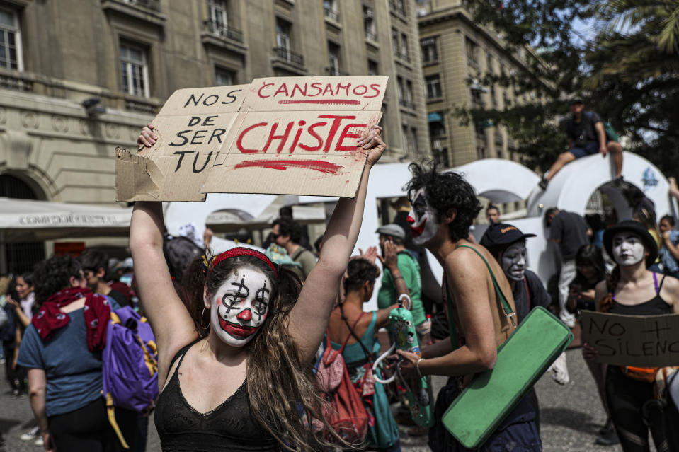 A woman holds a sign that reads in Spanish “We are tired of being your joke” as Artists, clowns, mimes and actors protest against President Sebastian Piñera’s government, at the Plaza de Armas in Santiago, Chile, Wednesday, Oct. 23, 2019. Rioting, arson attacks and violent clashes wracked Chile as the government raised the death toll in an upheaval that has almost paralyzed the South American country long seen as the region's oasis of stability. (AP Photo/Esteban Felix)