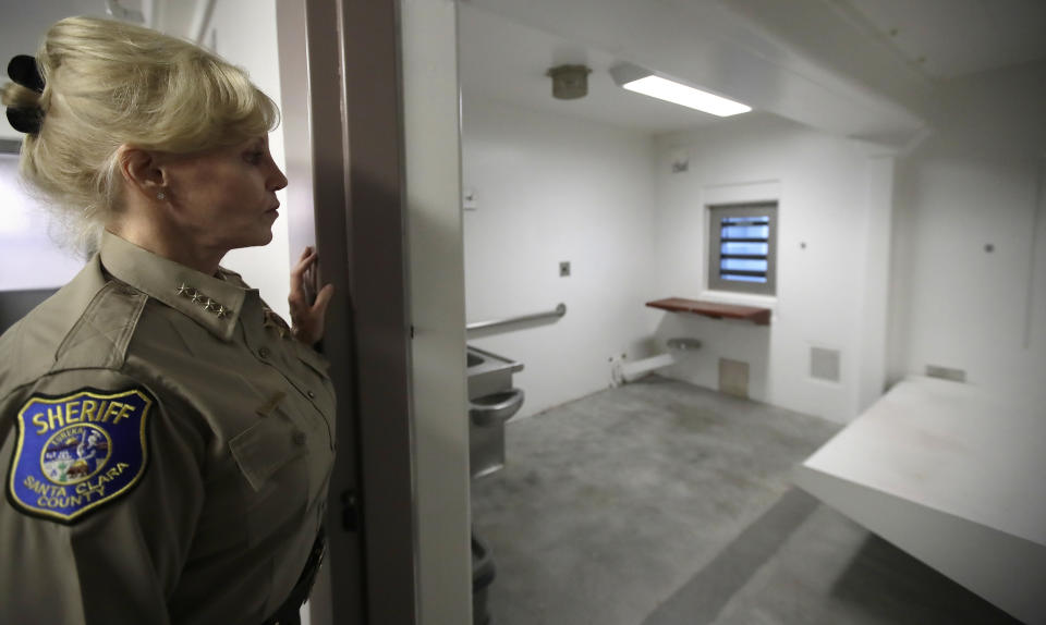 FILE - Santa Clara County Sheriff Laurie Smith looks into a solitary confinement cell at the Main Jail on Dec. 16, 2019, in San Jose, Calif. The trial of the longtime California sheriff on public corruption allegations involving her office's granting of concealed-carry weapons permits and costly jail mismanagement was set to begin with jury selection Wednesday, Sept. 21, 2022. (AP Photo/Ben Margot, File)