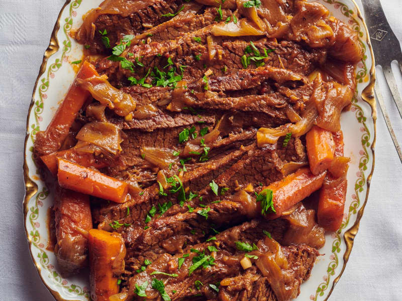 Dad's brisket on platter surrounded by roasted carrots and serving fork on side