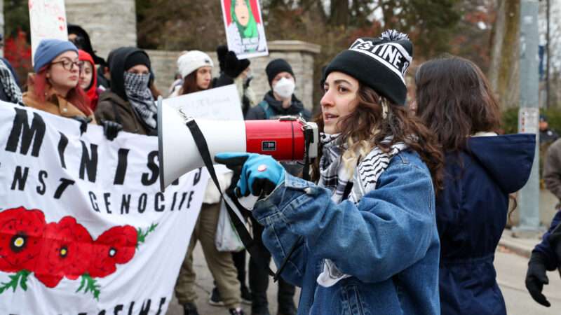 A young woman with a bullhorn leads a crowd in a pro-Palestine protest at Pennsylvania State Universtiy.