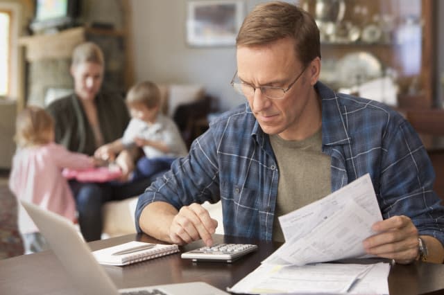 Father paying bills with family behind him