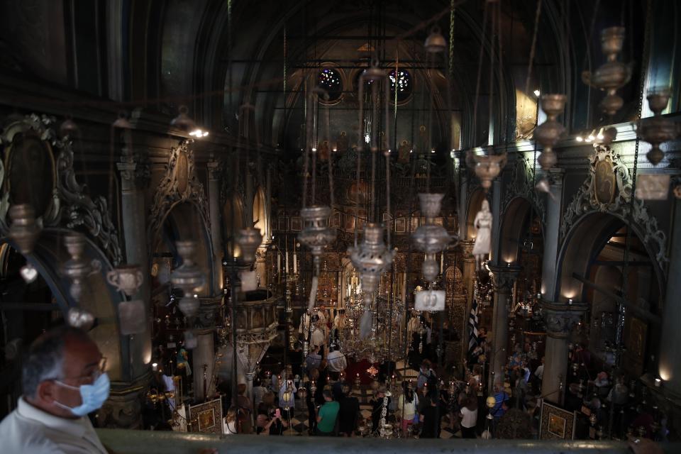 A man wearing a face mask against the spread of the new coronavirus, and other pilgrims attend a service in the Holy Church of Panagia of Tinos, on the Aegean island of Tinos, Greece, on Thursday, Aug. 13, 2020. For nearly 200 years, Greek Orthodox faithful have flocked to Tinos for the August 15 feast day of the Assumption of the Virgin Mary, the most revered religious holiday in the Orthodox calendar after Easter. But this year there was no procession, the ceremony _ like so many lives across the globe _ upended by the coronavirus pandemic. (AP Photo/Thanassis Stavrakis)