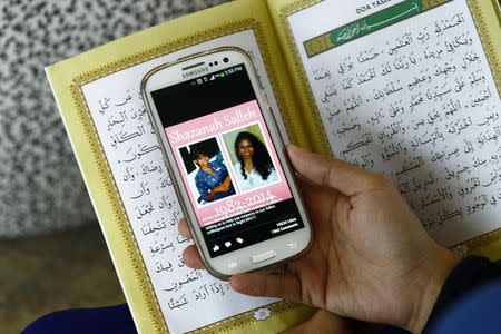 Siti Kartika Abdul Karim holds her mobile phone displaying a picture of her former schoolmate, Malaysia Airlines Flight MH17 flight attendant Nur Shazana Mohamed Salleh, during a special prayer for victims of the downed plane, at the Tuanku Mizan Zainal Abidin mosque in Putrajaya, outside Kuala Lumpur July 19, 2014. REUTERS/Samsul Said