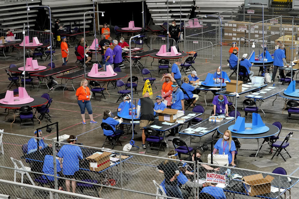 FILE - In this May 6, 2021, file photo, Maricopa County ballots cast in the 2020 general election are examined and recounted by contractors working for Florida-based company, Cyber Ninjas at Veterans Memorial Coliseum in Phoenix. Arizona’s largest county has approved nearly $3 million for new vote-counting machines to replace those given to legislative Republicans for a partisan review of the 2020 election. The GOP-controlled Maricopa County Board of Supervisors said Wednesday, July 14, 2021 that the machines were compromised because they were in the control of firms not accredited to handle election equipment. (AP Photo/Matt York, Pool, File)