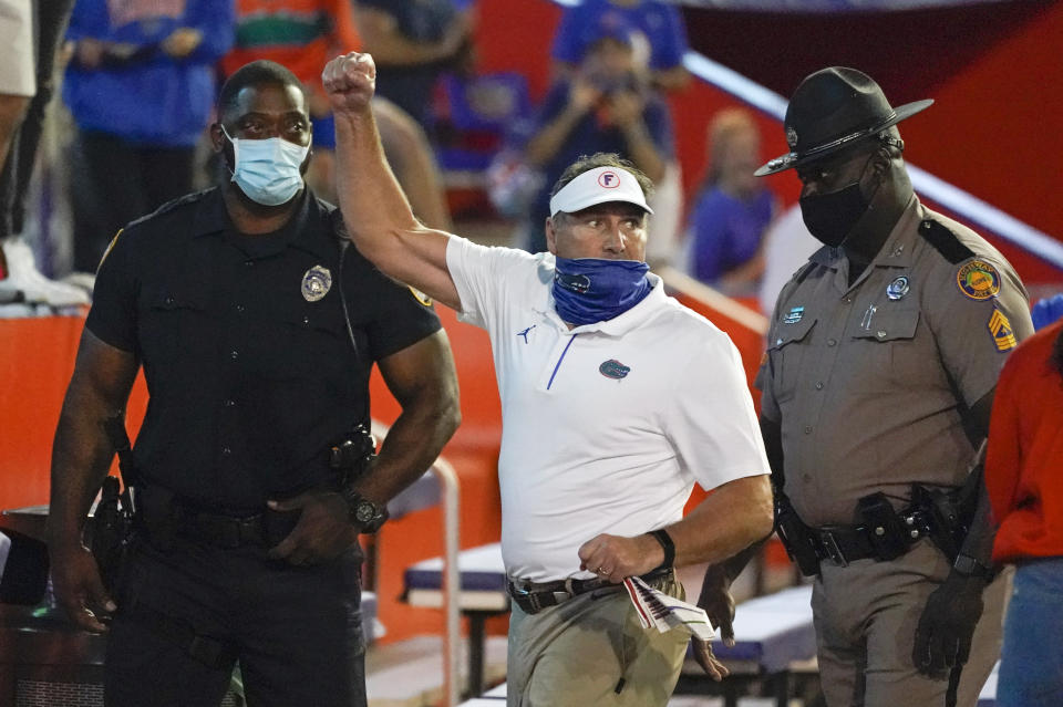 Florida head coach Dan Mullen, center, raises his fist to cheering Florida fans after an argument at the end of the first half as he was escorted to the locker room by law enforcement officers during an NCAA college football game against Missouri, Saturday, Oct. 31, 2020, in Gainesville, Fla. (AP Photo/John Raoux)