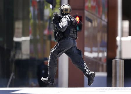 A police officer runs across Martin Place near Lindt cafe, where hostages are being held, in central Sydney December 15, 2014. REUTERS/David Gray