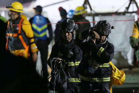 Members of rescue teams are pictured next to a collapsed building after an earthquake in Mexico City, Mexico September 28, 2017. REUTERS/Henry Romero