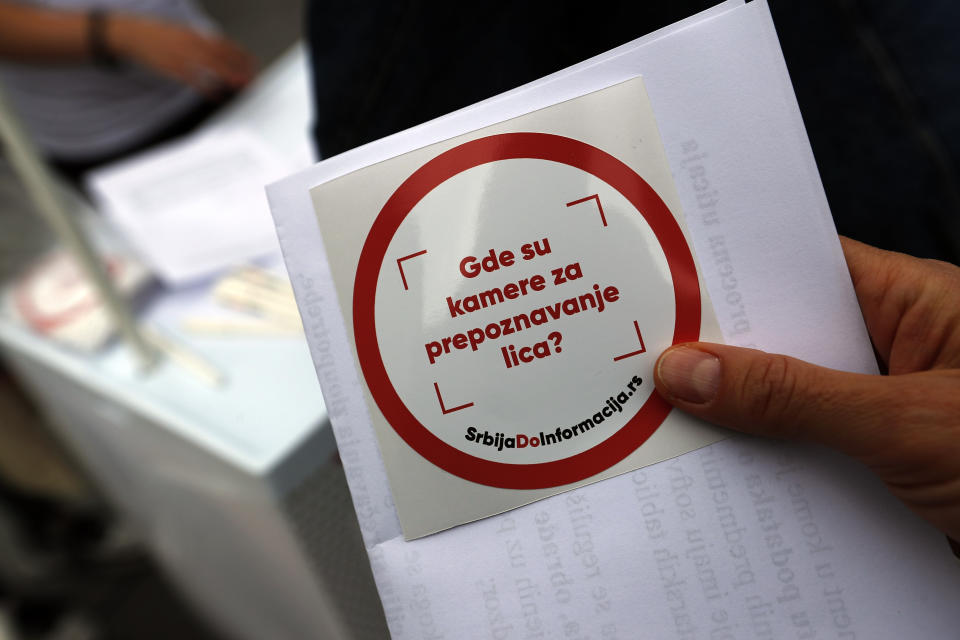 In this photo taken Sept. 25, 2019, an activist in the Serbian capital, Belgrade, shares stickers that read: ''Where are cameras for face recognition?'' With public authorities disclosing little about how the surveillance system works, the rights group has set up a tent to ask pedestrians whether they know they are being watched. (AP Photo/Darko Vojinovic)