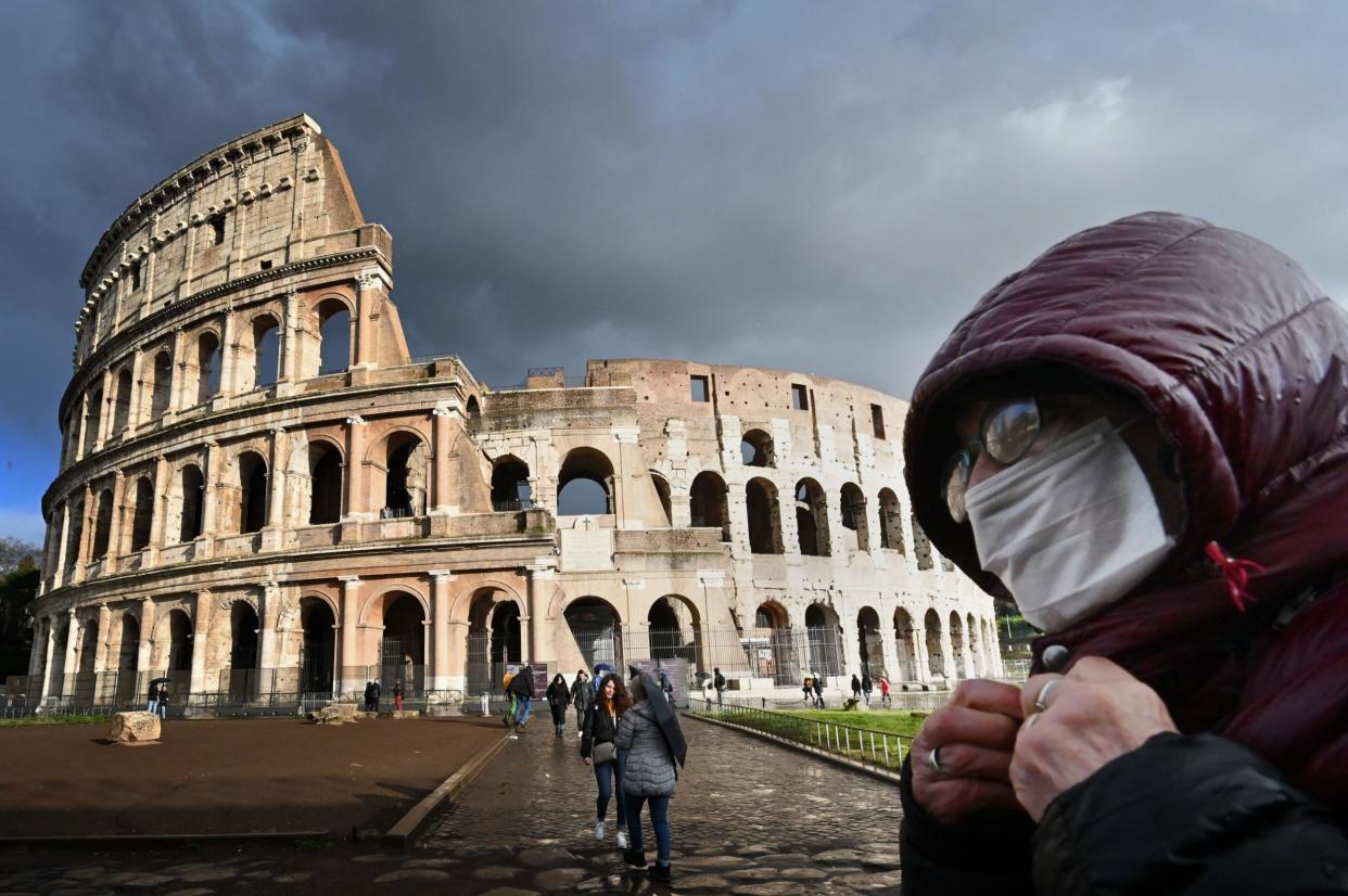 A man wearing a protective mask passes by the Coliseum in Rome: AFP via Getty Images