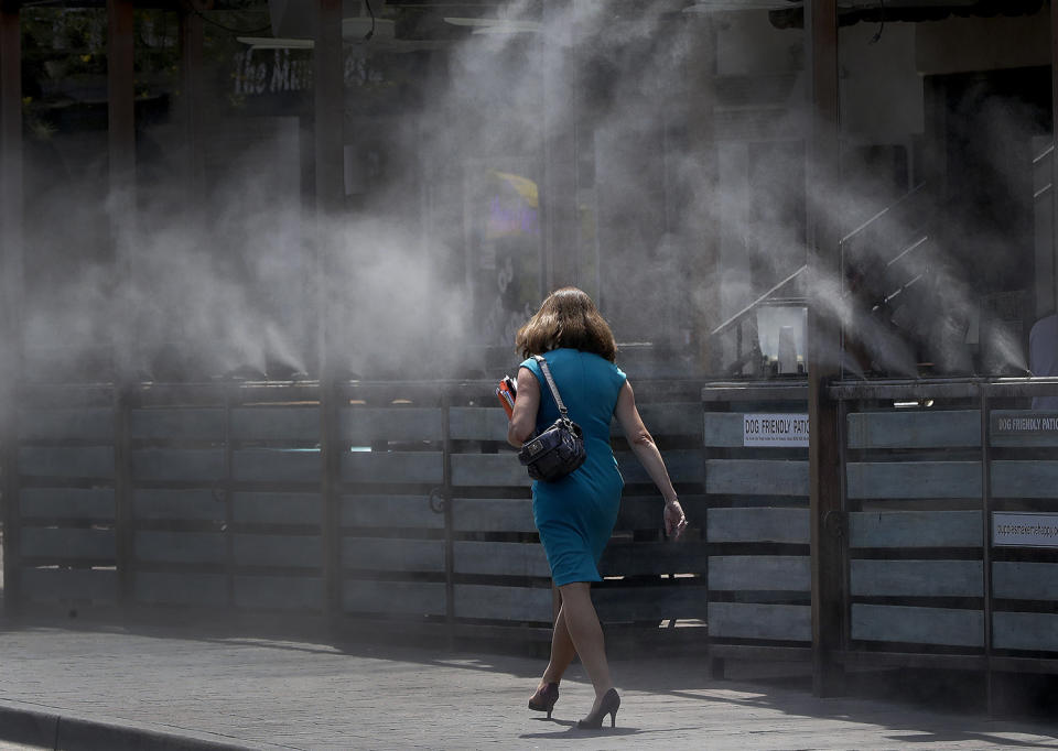 <p>A woman walks along a row of misters, June 19, 2017 in Tempe, Ariz. (Matt York/AP) </p>