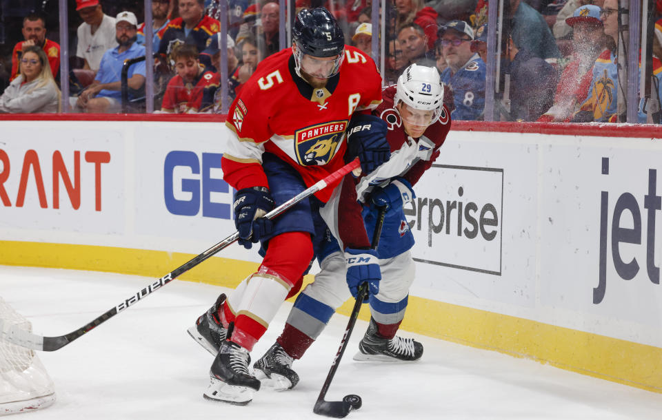 Florida Panthers defenseman Aaron Ekblad (5) and Colorado Avalanche center Nathan MacKinnon (29) vie for the puck during the first period of an NHL hockey game Saturday, Feb. 11, 2023, in Sunrise, Fla. (AP Photo/Reinhold Matay)