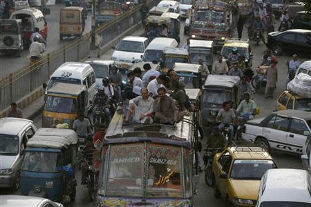 People sit atop a van in the traffic in Karachi September 3, 2013. Picture taken September 3, 2013. REUTERS/Stringer