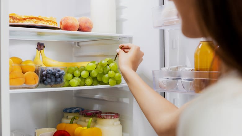woman removing grapes from refrigerator