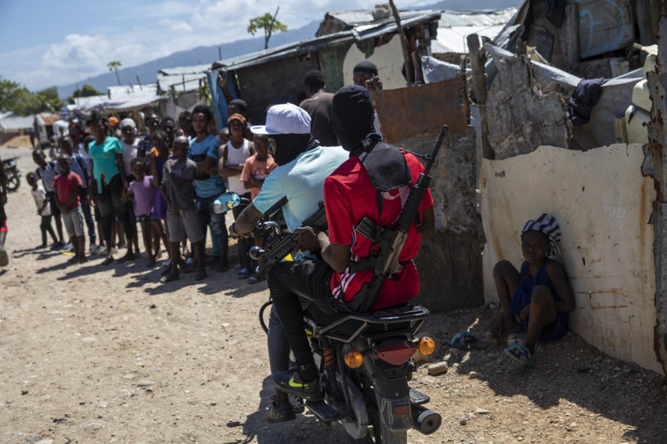 FILE - G9 coalition gang members ride a motorcycle through the Wharf Jeremy street market in Port-au-Prince, Haiti, Oct. 6, 2021. While some gangs have turned to kidnapping, like those who captured 17 missionaries and their relatives, Jimmy Cherizier, aka Barbecue, a former policeman who leads the G9 gang coalition, has taken control of the port district, gaining a stranglehold on the country's economy. (AP Photo/Rodrigo Abd, File)