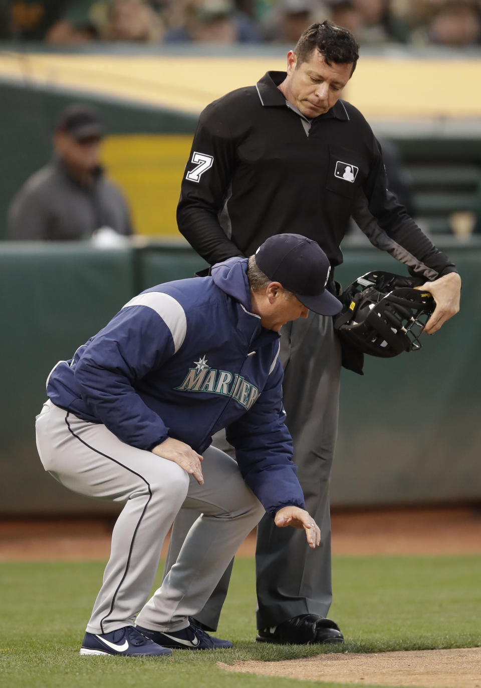 Seattle Mariners manager Scott Servais, left, squats at home plate as he speaks with umpire Carlos Torres in the fourth inning of a baseball game against the Oakland Athletics, Saturday, June 15, 2019, in Oakland, Calif. Servais was ejected from the game by Torres. (AP Photo/Ben Margot)