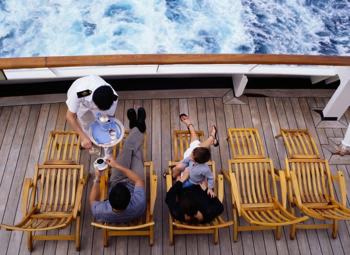 Server bringing family drinks as they lounge on cruise ship deck.