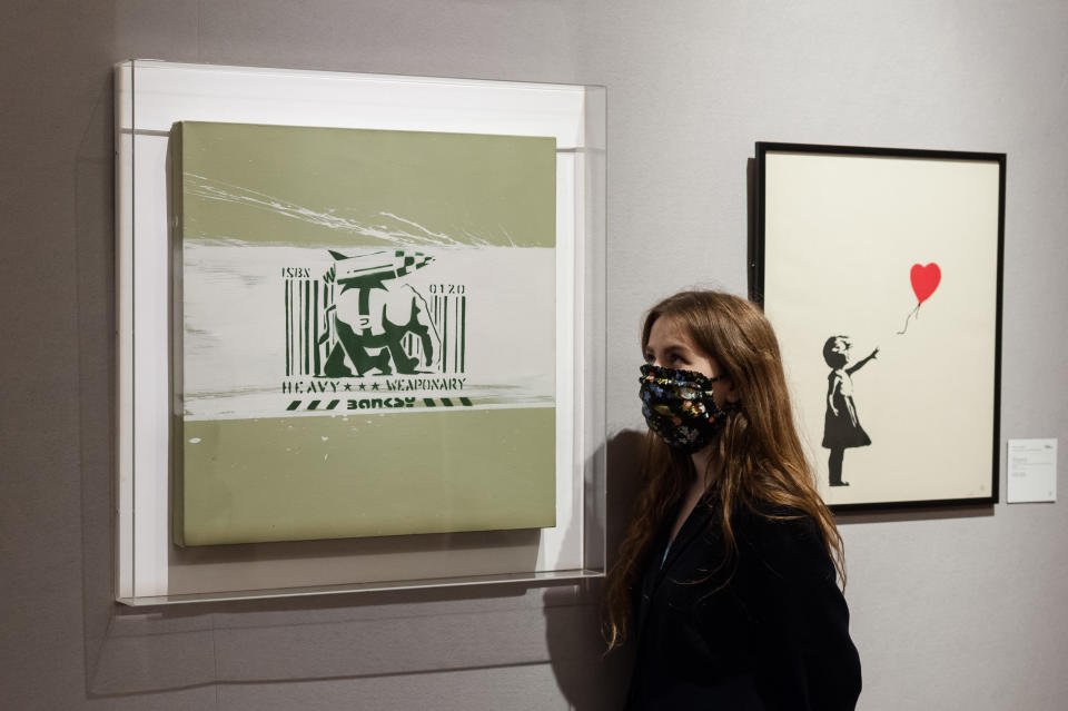 Empleada de la casa de subastas Bonhams de Londres posa junto a dos obras de Banksy a la venta.