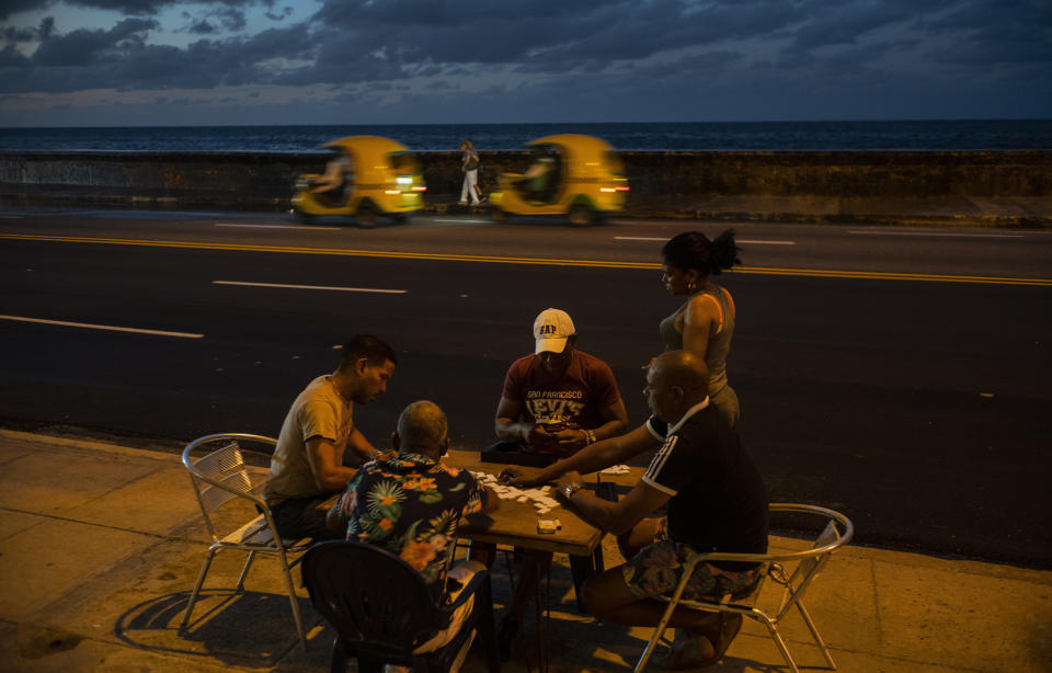 In this Nov. 10, 2019 photo, people play dominoes near the malecon sea wall at sunset in Havana, Cuba. The city will celebrate its 500th anniversary on Nov. 16. (AP Photo/Ramon Espinosa)