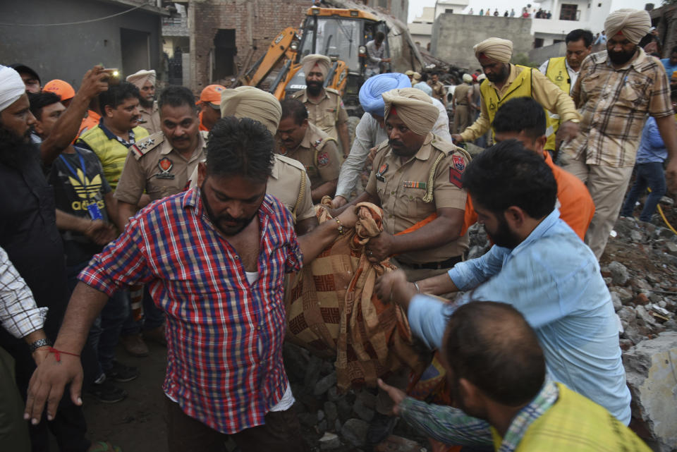 Rescuers carry the body of a victim at the site of an explosion at a fireworks factory in Batala, in the northern Indian state of Punjab, Wednesday, Sept. 4, 2019. More than a dozen people were killed in the explosion that caused the building to catch fire and collapse, officials said. (AP Photo/Prabhjot Gill)