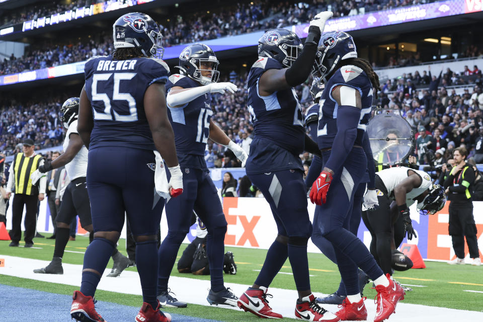 Tennessee Titans teammates congratulate running back Derrick Henry, right, after a touchdown against the Baltimore Ravens during the second half of an NFL football game Sunday, Oct. 15, 2023, at the Tottenham Hotspur stadium in London. (AP Photo/Ian Walton)