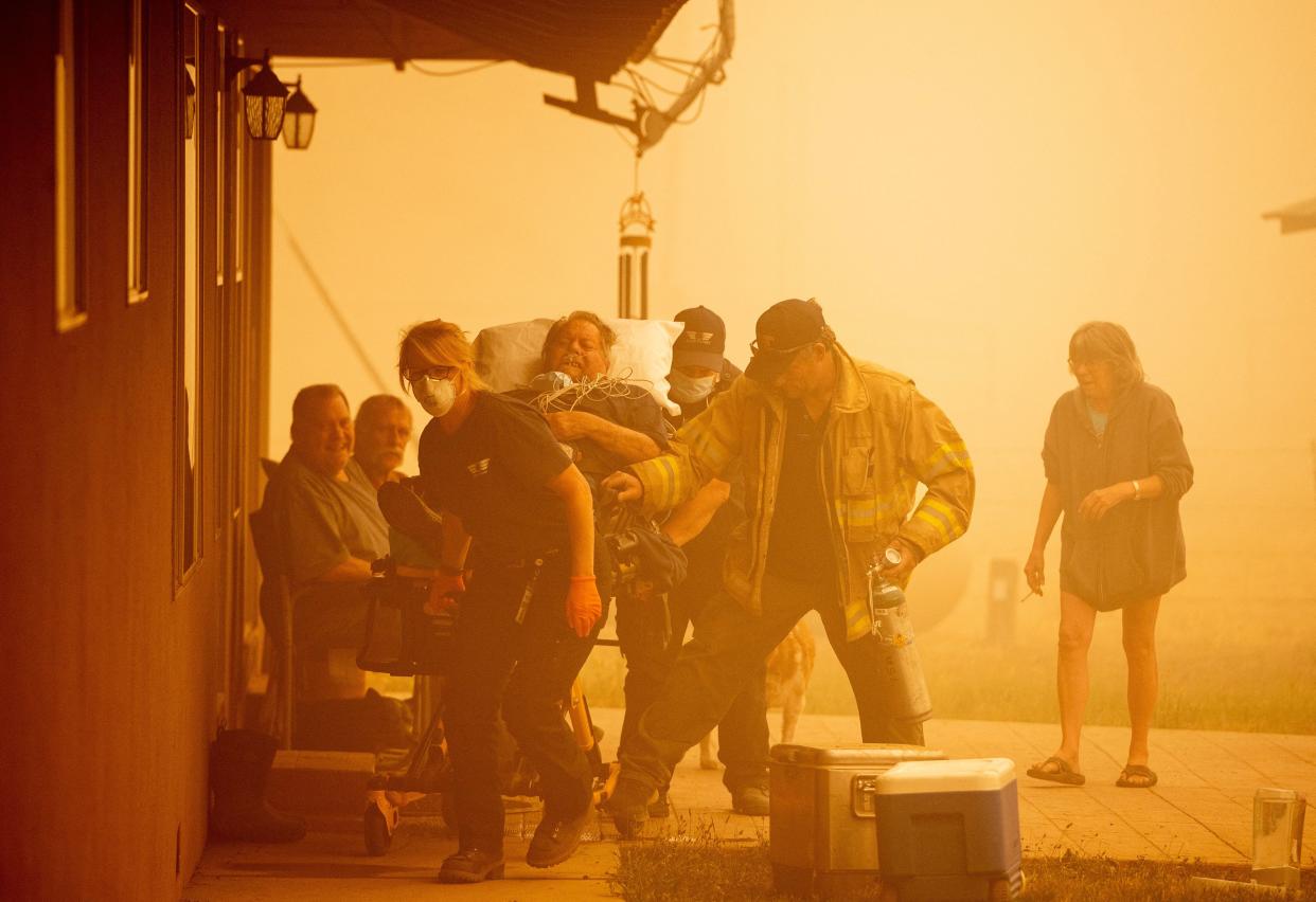 Firefighters and medical personnel rush Don Crail (C), 72, into an ambulance for a medical issue in Greenville, Calif. on Aug. 7, 2021.