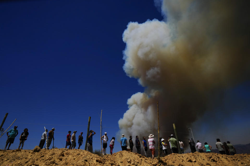 Residents watch as a plume of smoke from forest fires rises into the sky, in Vina del Mar, Chile, Saturday, Feb. 3, 2024. Officials say intense forest fires burning around a densely populated area of central Chile have left several people dead and destroyed hundreds of homes. (AP Photo/ Esteban Felix)